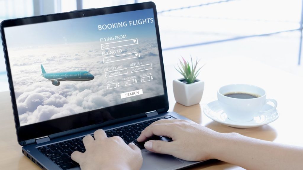 laptop displaying a flight booking website with travel details and options.